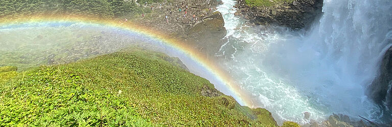 Regenbogen neben Wasserfall, im Hintergrund grünes Tal. (C) David Sporn
