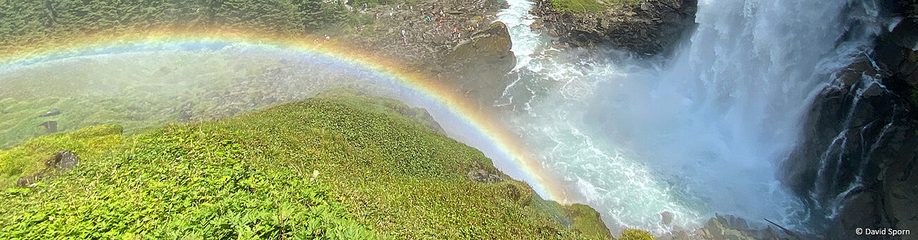 Regenbogen neben Wasserfall, im Hintergrund grünes Tal. (C) David Sporn
